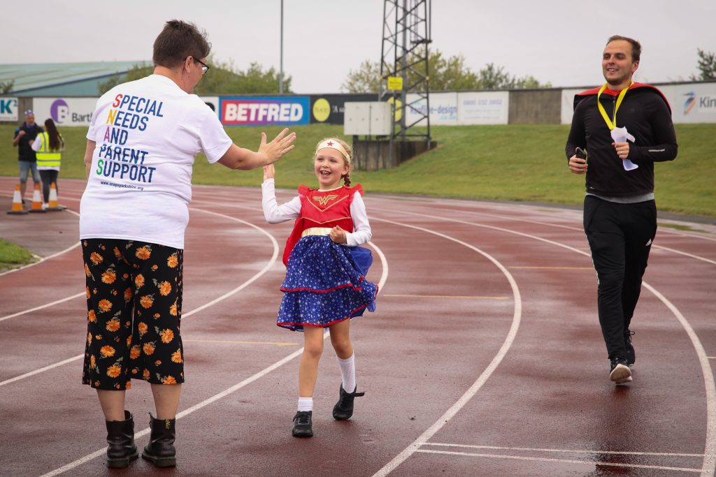 Child dressed as superhero reaching the finish line