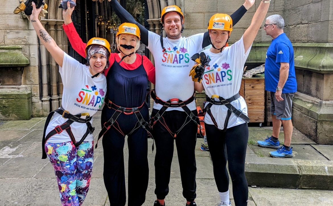 Group of SNAPS fundraIsers wearing harnesses for abseiling