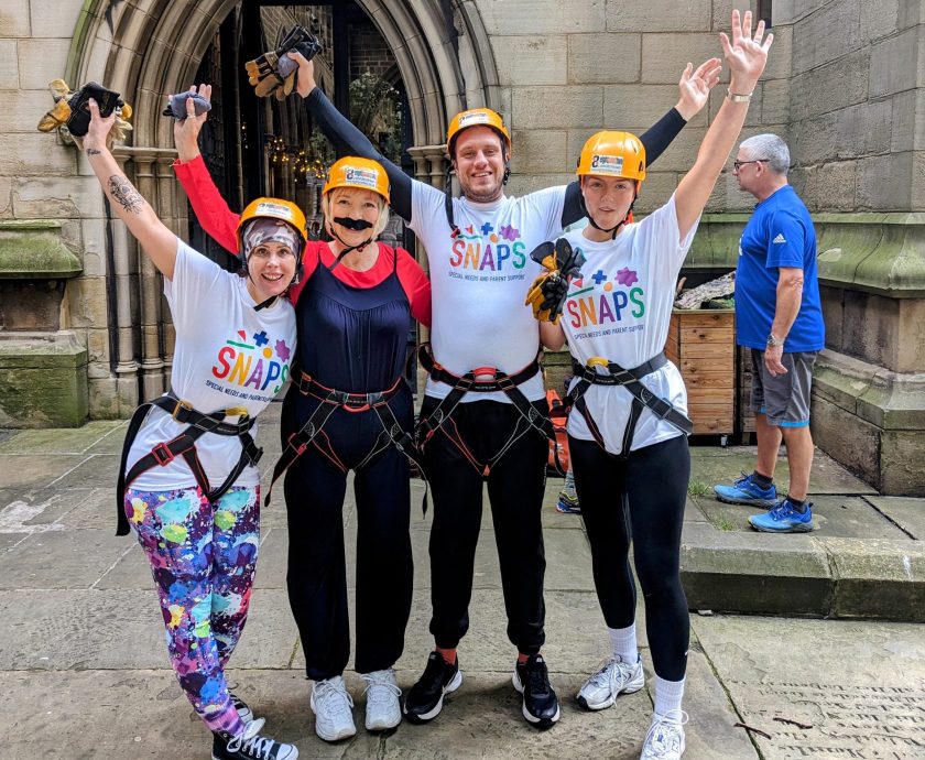 Group of SNAPS fundraIsers wearing harnesses for abseiling