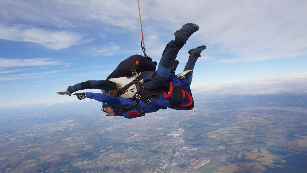 Two people taking part in a tandem skydive in the air