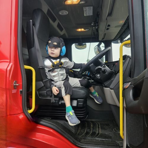 Young boy in a superhero costume sat in a Fire Engine