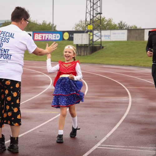 Child dressed as superhero reaching the finish line